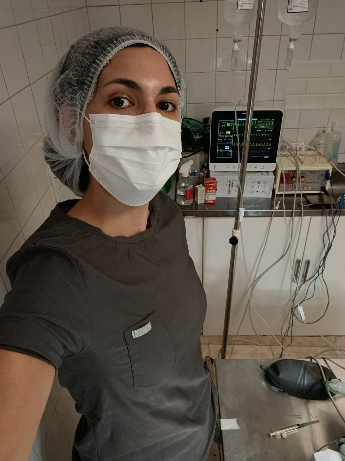 La Dra. Agustina Barchiessi con cofia y barbijo junto al monitor de signos vitales