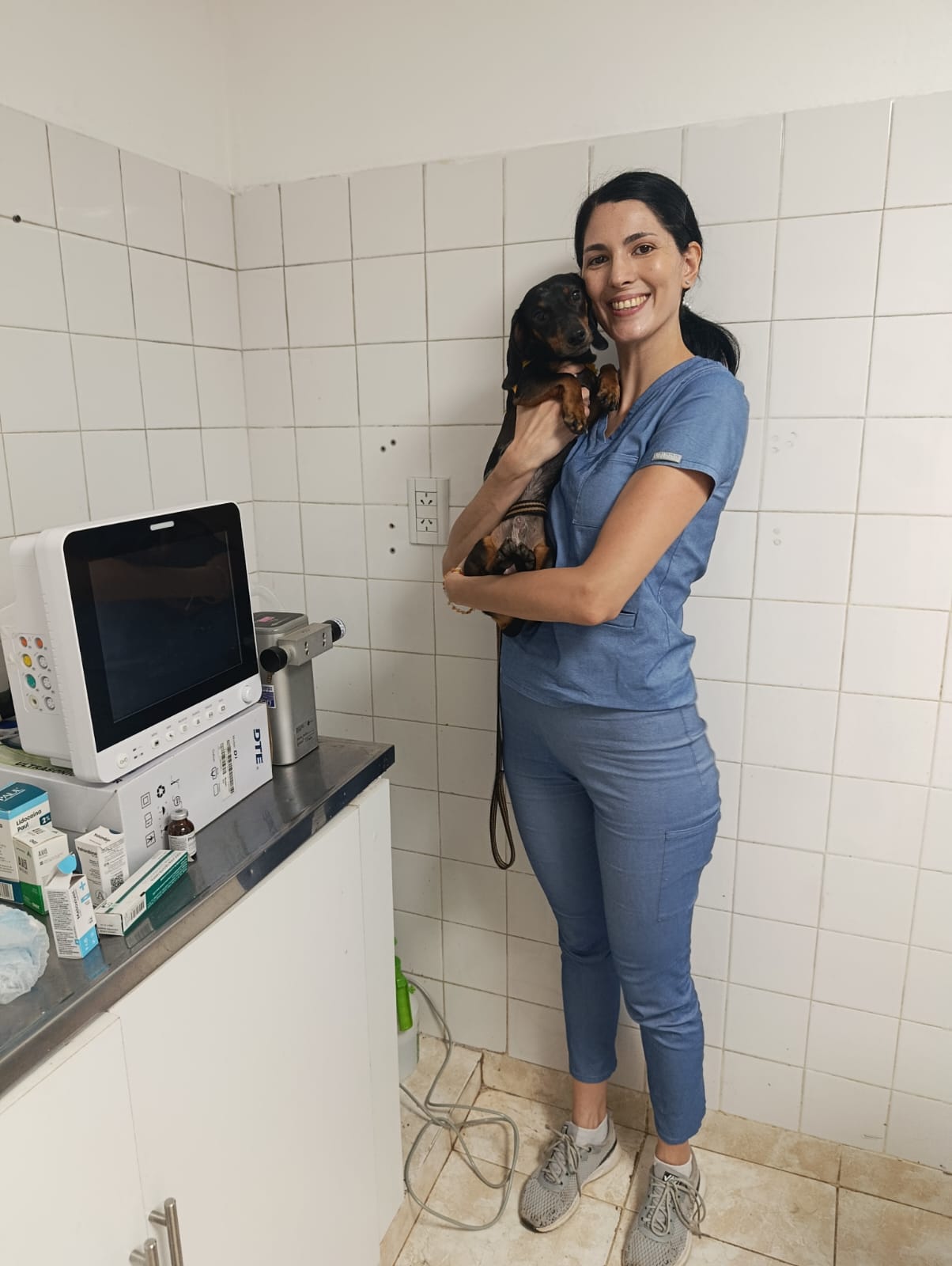 La Dra. Agustina Barchiessi en el consultorio de Clivad, sosteniendo a un perro salchicha